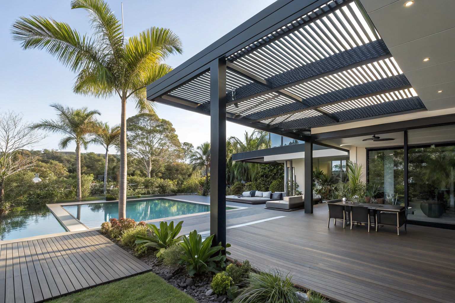 A modern black louvre-roof pergola over a timber deck beside an infinity pool