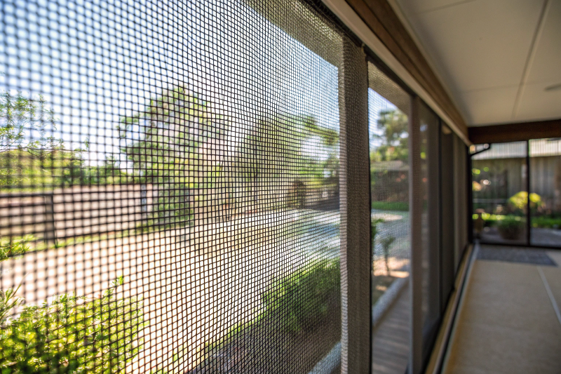 Close-up detail of fine mesh screening showing tight weave and transparency with garden visible beyond